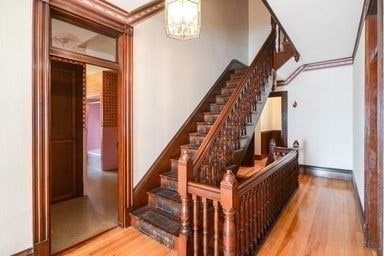 staircase featuring hardwood / wood-style floors, crown molding, and a chandelier