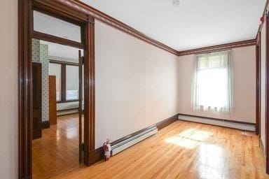 unfurnished room with hardwood / wood-style floors, a baseboard radiator, and ornamental molding