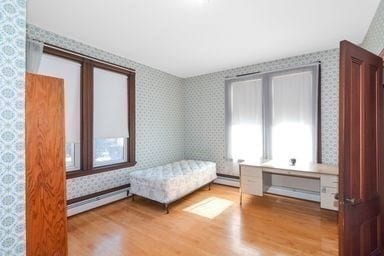 bedroom featuring baseboard heating, built in desk, and light hardwood / wood-style floors