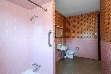 bathroom with toilet, tiled shower / bath, and tile walls