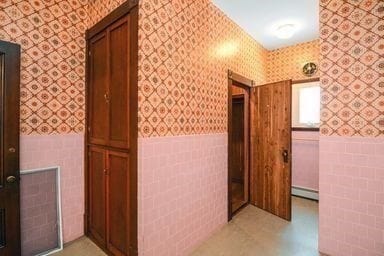 hall featuring a baseboard radiator and tile walls