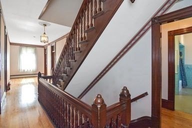 stairway featuring hardwood / wood-style floors and a baseboard heating unit