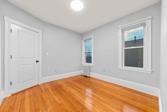 spare room with a wealth of natural light, wood-type flooring, and radiator