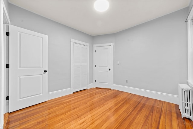 unfurnished bedroom featuring wood-type flooring and radiator heating unit