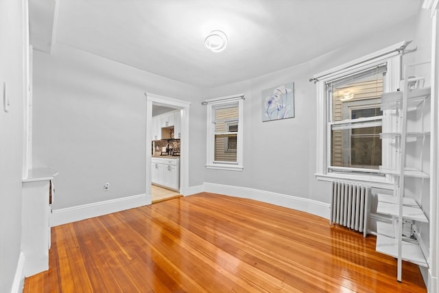 empty room with hardwood / wood-style flooring and radiator heating unit