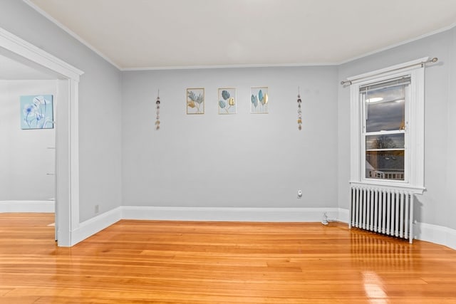 empty room with hardwood / wood-style floors, radiator heating unit, and crown molding