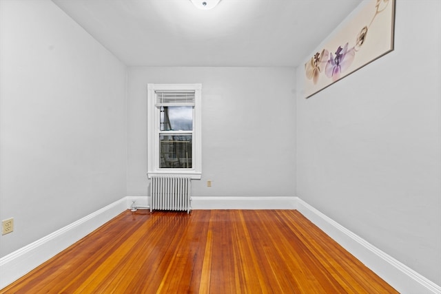 unfurnished room with radiator heating unit and hardwood / wood-style floors