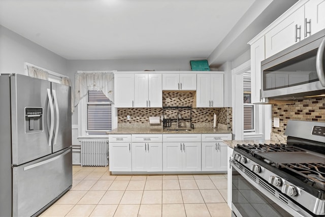 kitchen with radiator, appliances with stainless steel finishes, sink, and white cabinets