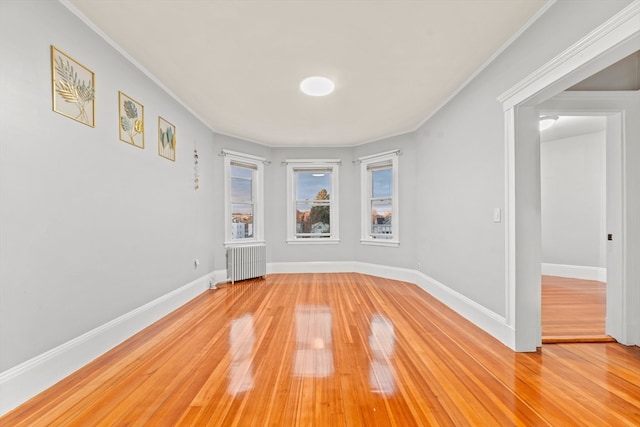 empty room featuring radiator heating unit, wood-type flooring, and ornamental molding