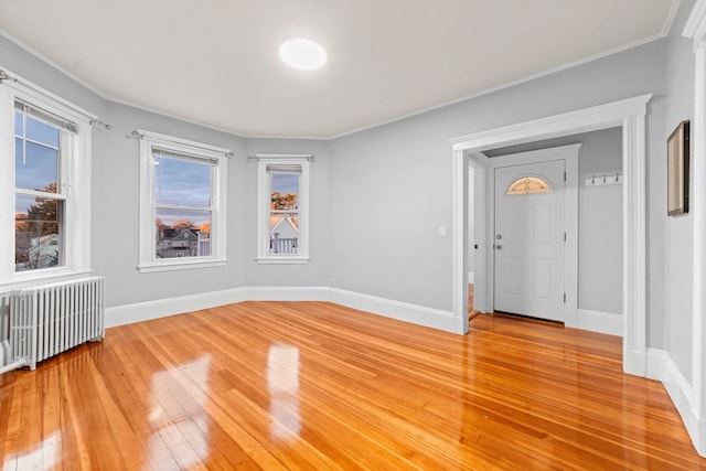 spare room with ornamental molding, light wood-type flooring, and radiator heating unit