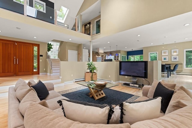 28 Elm St, Berkley, MA 02779 - living area with a baseboard heating unit, stairs, light wood-style floors, recessed lighting, and a towering ceiling