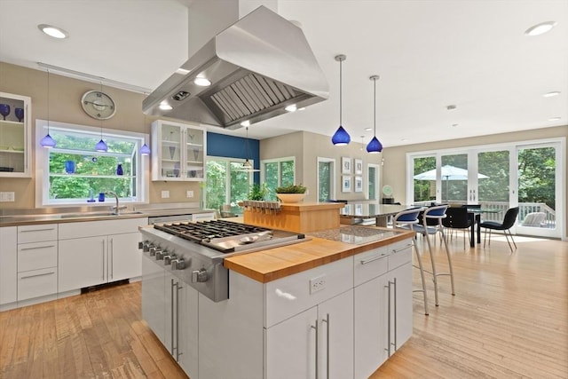 28 Elm St, Berkley, MA 02779 - kitchen featuring island exhaust hood, stainless steel gas stovetop, stainless steel countertops, light wood finished floors, and white cabinets