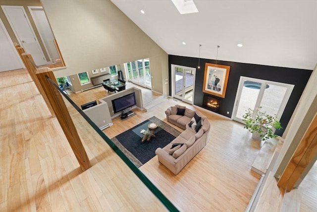 28 Elm St, Berkley, MA 02779 - living room with a warm lit fireplace, a skylight, wood finished floors, high vaulted ceiling, and recessed lighting