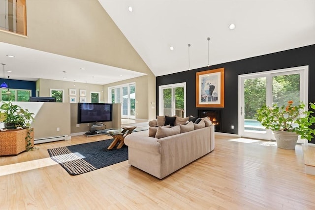 28 Elm St, Berkley, MA 02779 - living area with baseboard heating, light wood finished floors, a warm lit fireplace, high vaulted ceiling, and recessed lighting