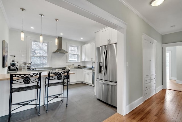 137 Freeman St Unit 3A, Brookline, MA 02446 - kitchen with stainless steel refrigerator with ice dispenser, wall chimney exhaust hood, tasteful backsplash, white cabinetry, and crown molding