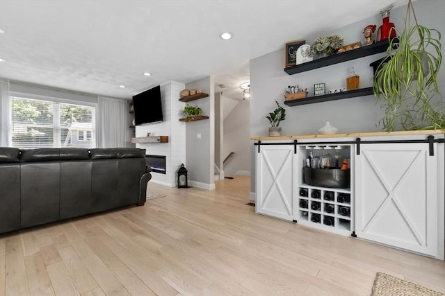 27 Harnden Rd, Billerica, MA 01821 - living room featuring light wood finished floors, recessed lighting, baseboards, a barn door, and a fireplace