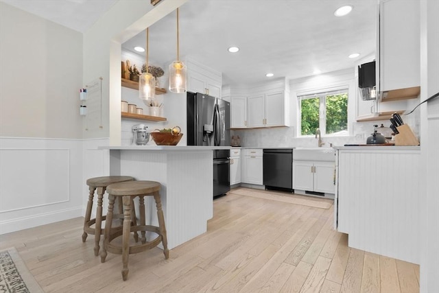 27 Harnden Rd, Billerica, MA 01821 - kitchen featuring black appliances, a peninsula, light wood-style floors, white cabinets, and a wainscoted wall