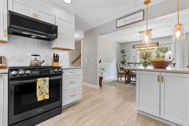 27 Harnden Rd, Billerica, MA 01821 - kitchen with stainless steel gas stove, light wood finished floors, white cabinets, light countertops, and decorative backsplash