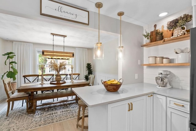 27 Harnden Rd, Billerica, MA 01821 - kitchen featuring open shelves, light wood-type flooring, light countertops, a peninsula, and hanging light fixtures