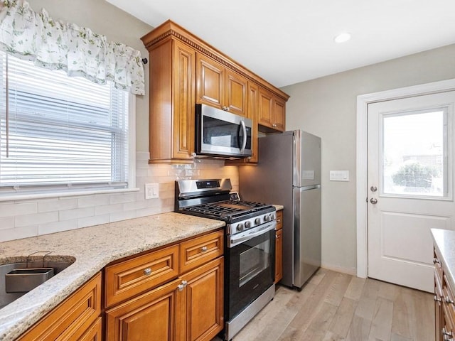 55 Bruce Rd, Waltham, MA 02453 - kitchen with stainless steel appliances, brown cabinetry, light wood finished floors, tasteful backsplash, and recessed lighting