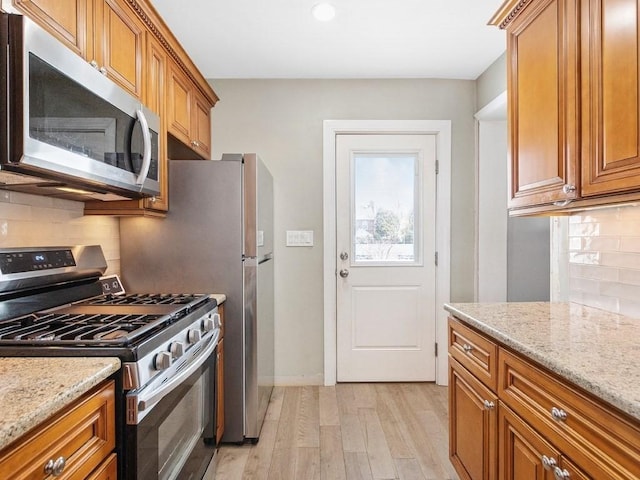 55 Bruce Rd, Waltham, MA 02453 - kitchen with appliances with stainless steel finishes, light wood-type flooring, brown cabinetry, tasteful backsplash, and recessed lighting