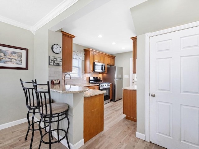55 Bruce Rd, Waltham, MA 02453 - kitchen with stainless steel appliances, ornamental molding, light wood-style flooring, baseboards, and a peninsula