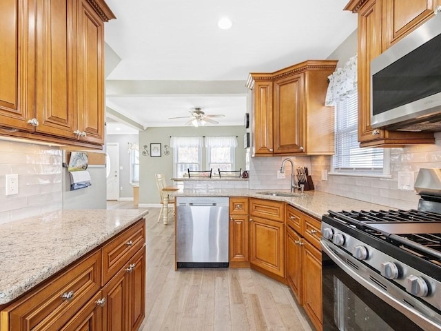 55 Bruce Rd, Waltham, MA 02453 - kitchen with stainless steel appliances, a sink, brown cabinets, light wood-type flooring, and light stone counters
