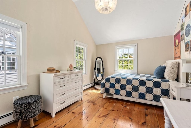 bedroom with vaulted ceiling, a baseboard heating unit, and light hardwood / wood-style flooring