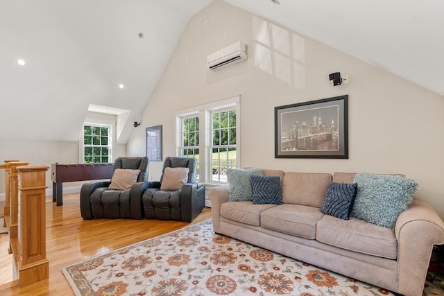 living room featuring vaulted ceiling, an AC wall unit, plenty of natural light, and light hardwood / wood-style flooring