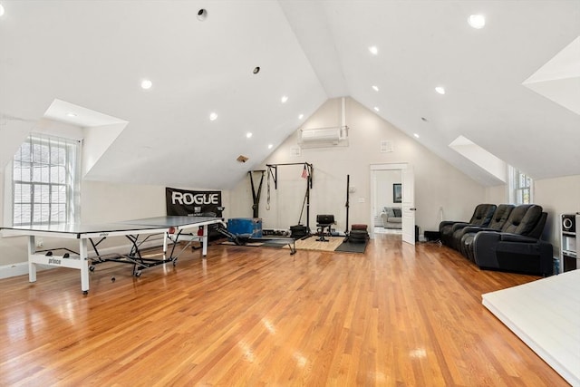 workout room with a wall mounted air conditioner, light hardwood / wood-style flooring, and vaulted ceiling