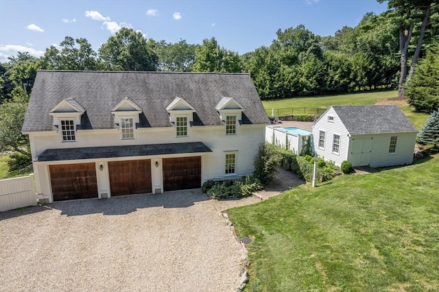 cape cod home featuring a garage, a front yard, and a shed