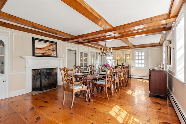 dining area featuring a baseboard radiator, wood-type flooring, and beam ceiling