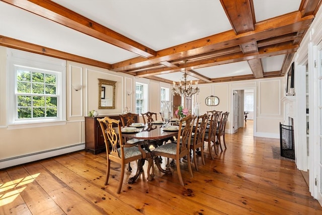 dining space featuring baseboard heating, a chandelier, beam ceiling, and light hardwood / wood-style floors