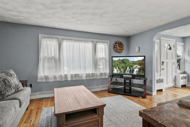 51 Crystal St, Lowell, MA 01852 - living area with radiator heating unit, arched walkways, wood finished floors, and a textured ceiling