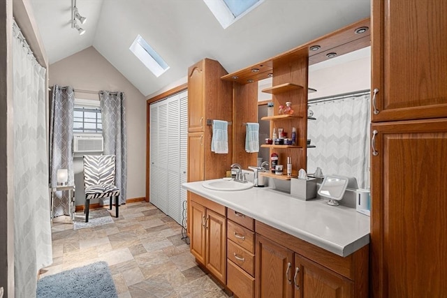 65 Holten St, Danvers, MA 01923 - bathroom with a skylight, vanity, vaulted ceiling, baseboards, and stone finish flooring