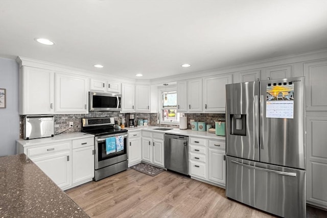 65 Holten St, Danvers, MA 01923 - kitchen with appliances with stainless steel finishes, light wood-style floors, tasteful backsplash, white cabinetry, and recessed lighting