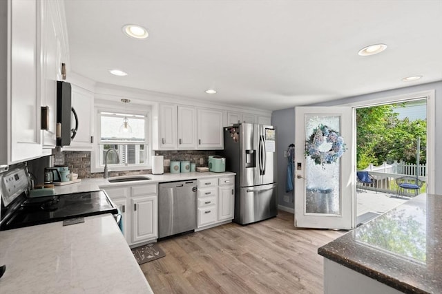 65 Holten St, Danvers, MA 01923 - kitchen with appliances with stainless steel finishes, a sink, decorative backsplash, white cabinetry, and light wood finished floors