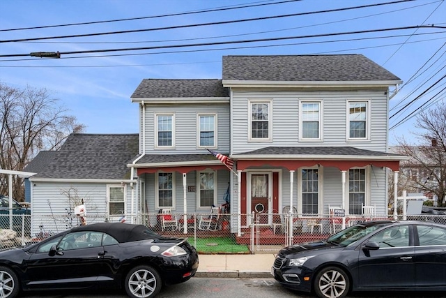 view of front of property with a porch, a fenced front yard, and roof with shingles