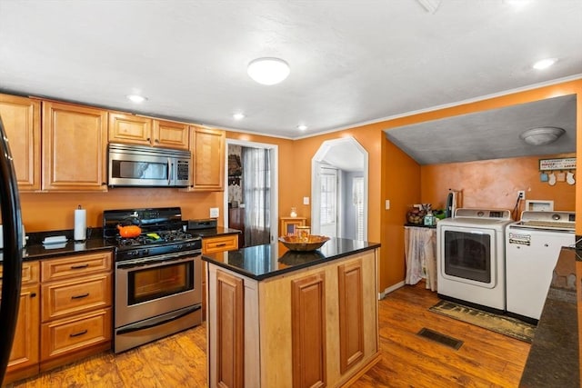 kitchen featuring separate washer and dryer, arched walkways, light wood finished floors, and stainless steel appliances