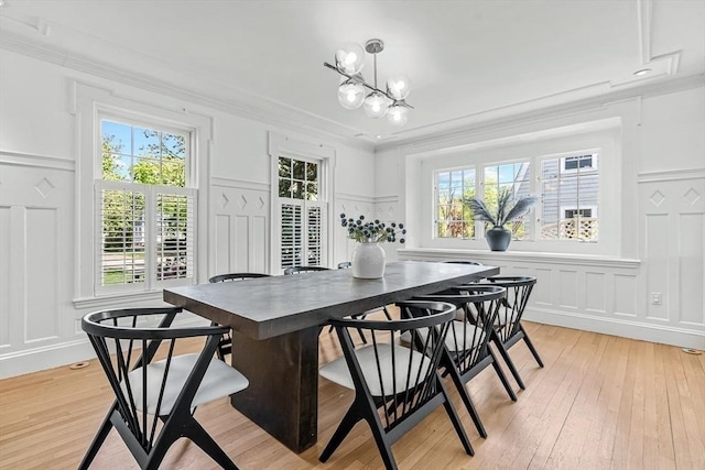 dining area featuring a decorative wall, plenty of natural light, crown molding, a chandelier, and light wood-type flooring