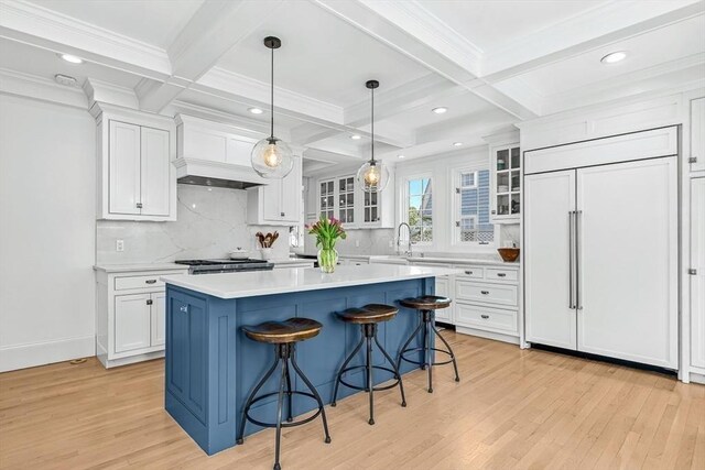 kitchen with paneled fridge, a sink, a kitchen breakfast bar, light wood-style flooring, and white cabinetry