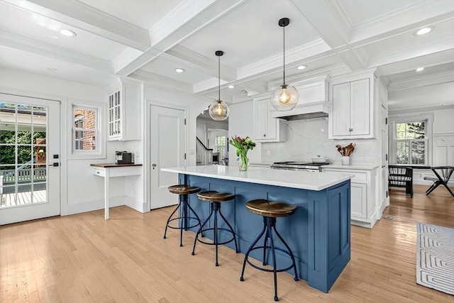kitchen featuring range, white cabinetry, light wood-style flooring, a kitchen breakfast bar, and light countertops