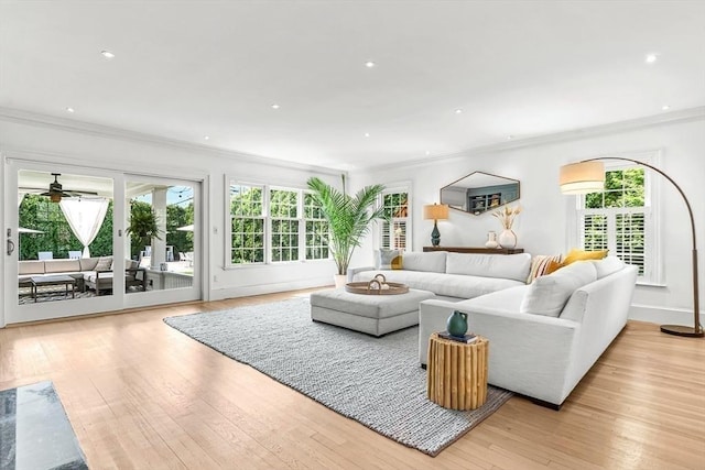 living room featuring crown molding, ceiling fan, light wood-style flooring, recessed lighting, and baseboards