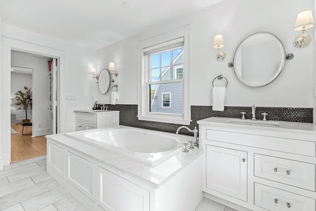 full bathroom featuring a bath, two vanities, and decorative backsplash
