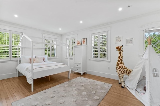 bedroom featuring crown molding, multiple windows, wood finished floors, baseboards, and recessed lighting