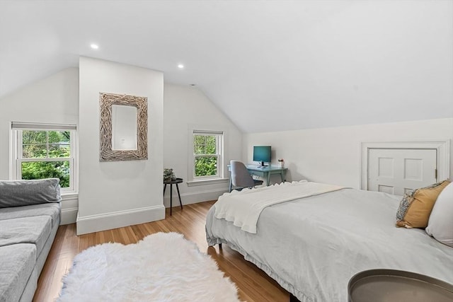 bedroom with lofted ceiling, light wood finished floors, and baseboards