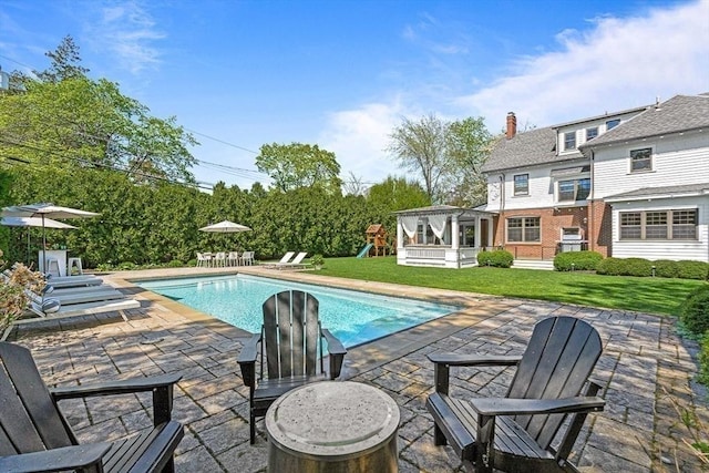 swimming pool with a patio area, a lawn, and a playground