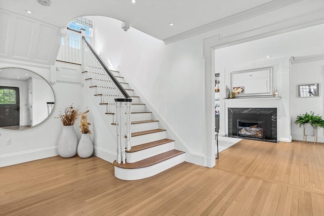 stairway with hardwood / wood-style flooring, a fireplace, baseboards, and ornamental molding