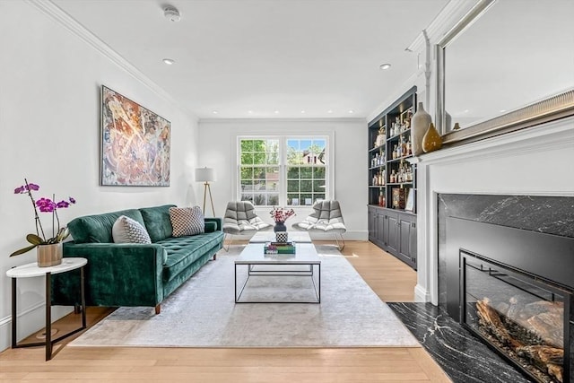 living room featuring a premium fireplace, wood finished floors, crown molding, baseboards, and recessed lighting