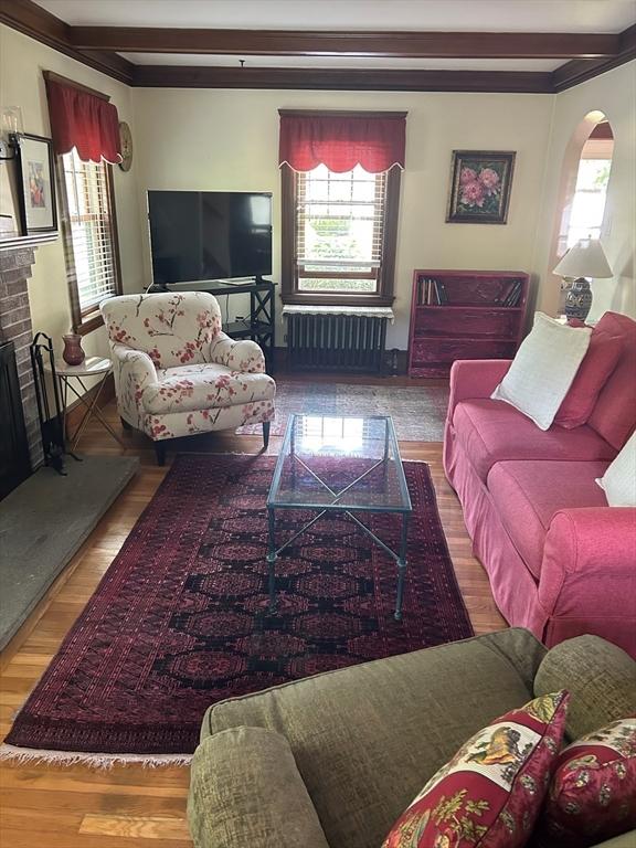 202 Madison St, Dedham, MA 02026 - living room featuring radiator heating unit, healthy amount of natural light, a brick fireplace, and arched walkways